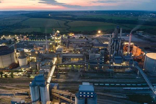 Yüksek beton yapılı çimento fabrikası ve endüstriyel üretim alanında geceleri kule vinçleri. Üretim ve küresel sanayi kavramı
