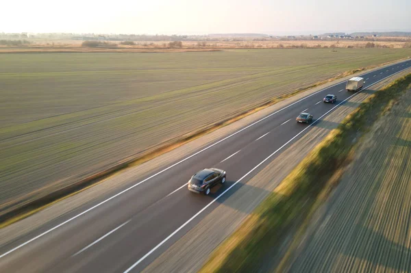 Вид с воздуха на междугороднюю дорогу с быстрыми автомобилями на закате. Вид сверху с дрона дорожного движения в вечернее время — стоковое фото