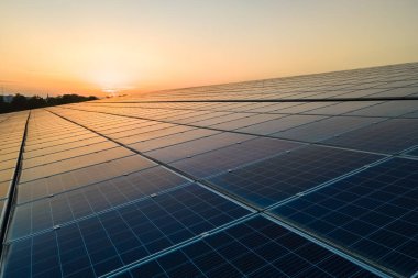 Mavi fotovoltaik güneş panelleri gün batımında temiz ekolojik elektrik üretmek için çatıya monte edildi. Yenilenebilir enerji konsepti üretimi