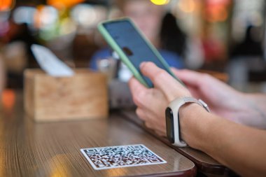 Konuk elin restoranda yemek sipariş ederken çevrimiçi menü için qr kodunu cep telefonuyla taraması