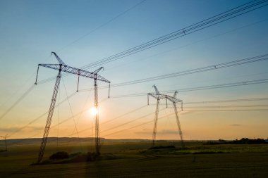 Güneş doğarken elektrik hatları olan yüksek voltajlı kulelerin koyu gölgesi.