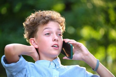 Genç bir çocuk, yaz parkında cep telefonuyla konuşurken tartışıyor. Gençlik yıllarındaki çatışma durumları