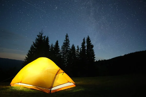 Ljusa upplysta turisttält som lyser på campingplatsen i mörka berg under natthimlen med gnistrande stjärnor. Begreppet aktiv livsstil — Stockfoto