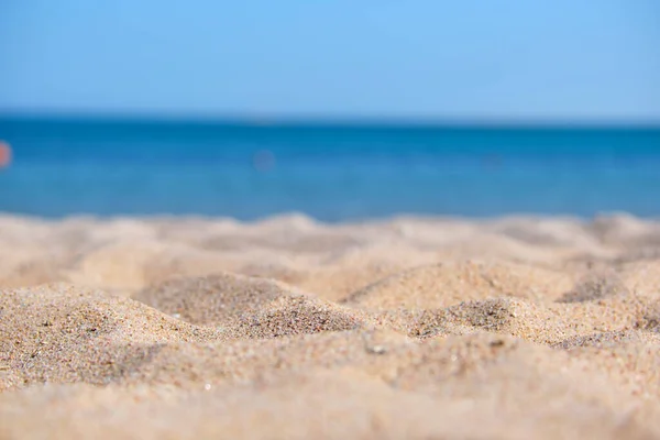 Κοντινό πλάνο καθαρής κίτρινης επιφάνειας άμμου που καλύπτει την παραλία με καταγάλανα νερά στο βάθος. Έννοια ταξιδιού και διακοπών — Φωτογραφία Αρχείου