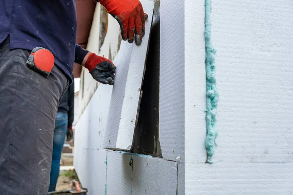 Byggnadsarbetare installera styrofoam isolering ark på huset fasadvägg för värmeskydd — Stockfoto