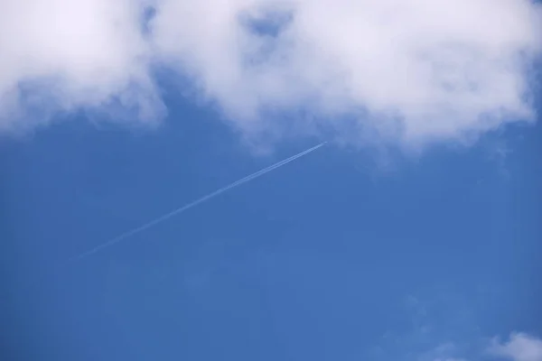 Entfernte Passagierflugzeuge fliegen in großer Höhe am blauen Himmel mit weißen Wolken, die Rauchspuren von Kondensstreifen hinterlassen. Flugreisekonzept — Stockfoto