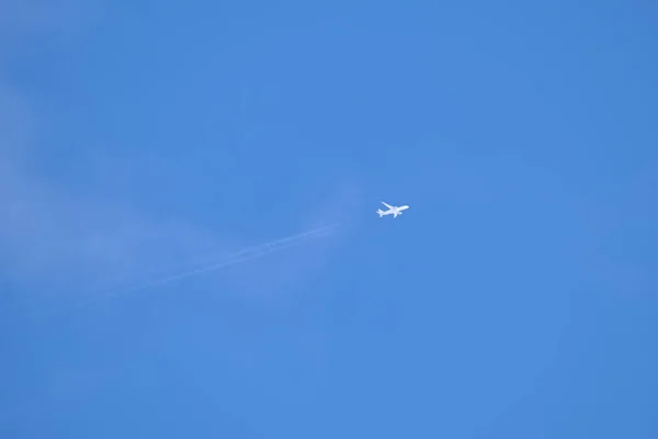 Avião de passageiros distantes voando em alta altitude no céu azul claro deixando vestígios de fumaça branca de contrail para trás. Conceito de transporte aéreo — Fotografia de Stock