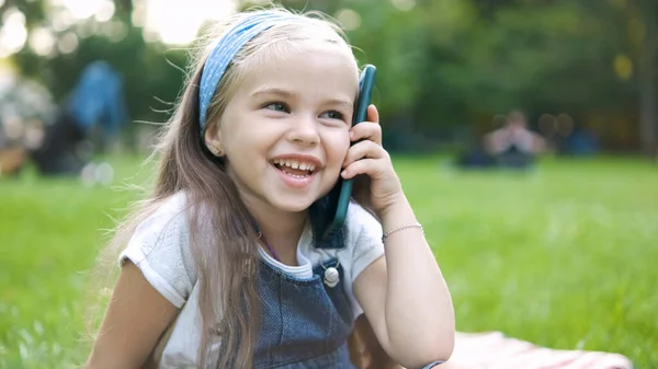 Niña feliz hablando por teléfono móvil en el parque de verano — Foto de Stock