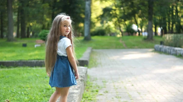 Pequeña niña bonita caminando al aire libre en el verde parque de verano — Foto de Stock