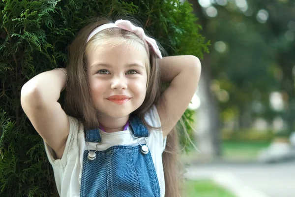 Porträtt av söt barn flicka stående i sommarparken tittar i kameran ler glatt — Stockfoto