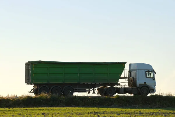 Semi-vrachtwagen met kipwagen die 's avonds zand vervoert uit steengroeve en over de snelweg vervoert. Levering transport en logistiek concept — Stockfoto
