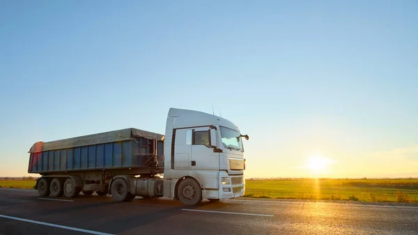 Semi-vrachtwagen met kipwagen die 's avonds zand vervoert uit steengroeve en over de snelweg vervoert. Levering transport en logistiek concept — Stockfoto