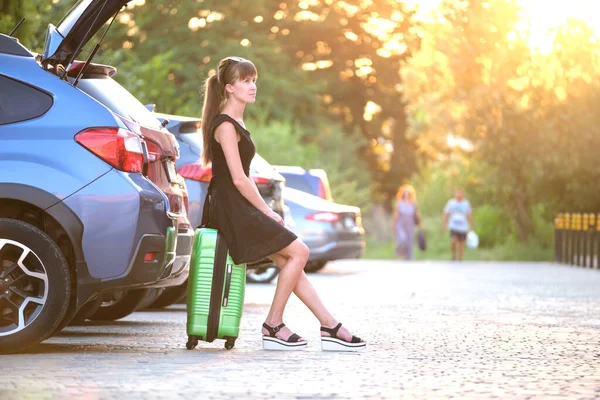 Mujer joven con maleta esperando al lado del coche. Concepto de viajes y vacaciones — Foto de Stock