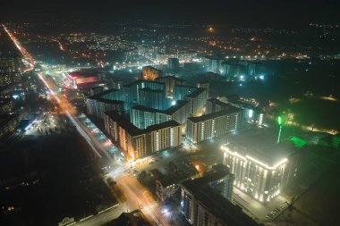 Yüksek katlı apartman binalarının ve şehrin yerleşim alanındaki aydınlık sokakların havadan görüntüsü. Karanlık şehir manzarası