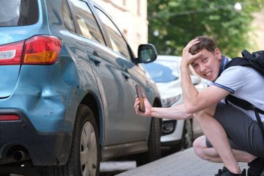 Hüzünlü erkek sürücü, trafik kazasından sonra sigorta hizmeti için cadde kenarındaki cep telefonu kamerasıyla kaza yapmış. Yol güvenliği kavramı