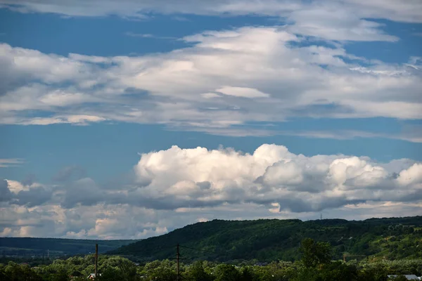 Яркий пейзаж белых пышных кучевых облаков на голубом ясном небе над сельской местностью — стоковое фото