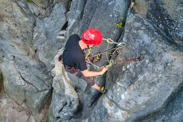 Determined climber clambering up steep wall of rocky mountain. Sportsman overcoming difficult route. Engaging in extreme sports and rock climbing hobby concept — Stock Photo, Image