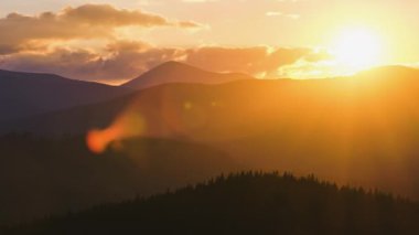 Güzel bir akşam panoramik manzarası. Gün batımında uzak dağ tepeleri üzerinde parlak batan güneş.