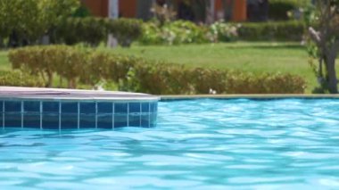 Mavi berrak su ve tropikal tatil köyündeki yüzme havuzunda küçük dalgalar. Yaz tatilleri konsepti