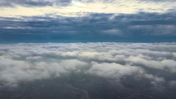 Vista aérea desde gran altitud de la ciudad distante cubierta de nubes de cúmulos hinchados que se forman antes de la tormenta. Punto de vista del avión del paisaje nublado — Vídeo de stock