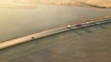 Gün batımında hızlı giden arabalarla şehirlerarası yol manzarası. Akşamları otoban trafiğinin insansız hava aracı görüntüsü