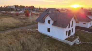 Havalandırılmış hafif beton duvarları ve inşaat halindeki metalik fayanslarla kaplı ahşap çatı iskeleti olan bitmemiş evin havadan görüntüsü.