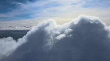 Dünya 'nın yüksek irtifasındaki uçak penceresinden hava manzarası beyaz kabarık kümülüs bulutlarıyla kaplı.