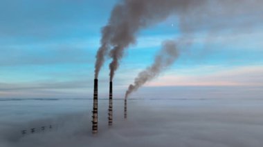 Kömür santralinin hava manzarası siyah dumanlı yüksek borular gün batımında atmosferi kirletiyor