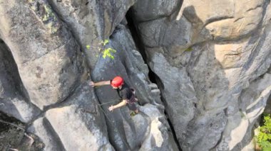 Güçlü erkek tırmanıcı kayalık dağın dik duvarına tırmanıyor. Sporcu zor yolu aştı. Ekstrem spor hobisi konsepti