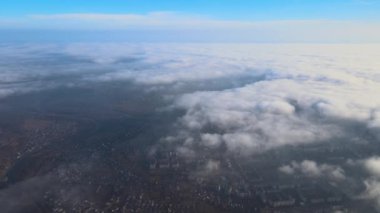 Fırtınadan önce, şişkin kümülüs bulutlarıyla kaplı uzak şehrin yüksek irtifasından gelen hava manzarası. Bulutlu havada uçak manzarası