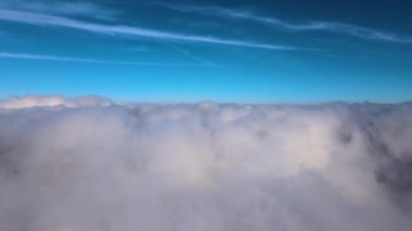 Güneşli bir günde, yeryüzünün yüksek irtifasından beyaz kabarık kümülüs bulutlarıyla kaplı hava manzarası.