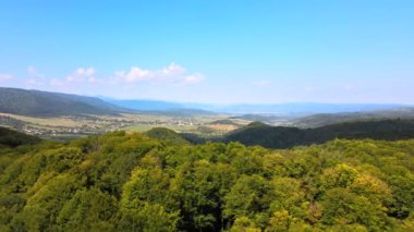 Parlak yaz gününde yoğun yeşil gür ormanlarla kaplı dağ tepelerinin havadan görünüşü