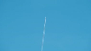 Mesafeli yolcu jet uçağı açık mavi gökyüzünde yüksek irtifada uçarken ardında beyaz duman izi bırakıyor. Hava taşımacılığı kavramı