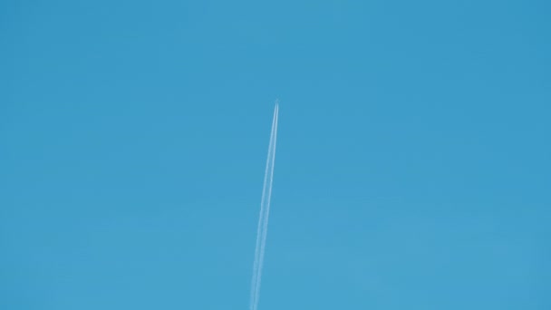 Avião de passageiros distantes voando em alta altitude no céu azul claro deixando vestígios de fumaça branca de contrail para trás. Conceito de transporte aéreo — Vídeo de Stock