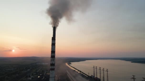 日没時に黒い煙が大気を汚染上に移動する石炭火力発電所の高いパイプの空中ビュー。化石燃料をコンセプトとした電気エネルギーの生産 — ストック動画
