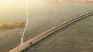 Gün batımında hızlı giden arabalarla şehirlerarası yol manzarası. Akşamları otoban trafiğinin insansız hava aracı görüntüsü