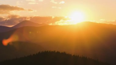 Güzel bir akşam panoramik manzarası. Gün batımında uzak dağ tepeleri üzerinde parlak batan güneş.