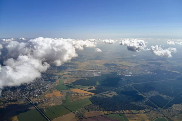 Αεροφωτογραφία από το παράθυρο του αεροπλάνου σε μεγάλο υψόμετρο της γης που καλύπτεται με φουσκωτά σύννεφα που σχηματίζουν σωρός πριν από την καταιγίδα — Φωτογραφία Αρχείου