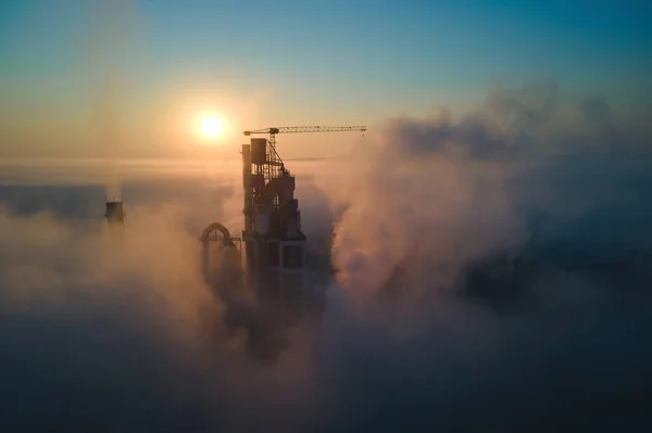 霧の朝に工業生産現場で高いコンクリート工場構造とタワークレーンとセメント工場の空中ビュー。製造業とグローバル産業の概念 — ストック写真