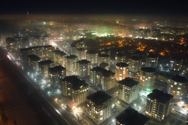 Yüksek katlı apartman binalarının ve şehrin yerleşim alanındaki aydınlık sokakların havadan görüntüsü. Karanlık şehir manzarası