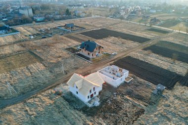 Havalandırılmış hafif beton duvarları ve yapım aşamasındaki ahşap çatı iskeleti olan bitmemiş özel evin havadan görüntüsü.