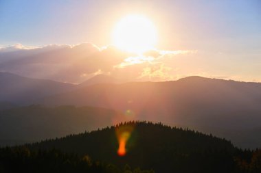 Güzel bir akşam panoramik manzarası. Gün batımında uzak dağ tepeleri üzerinde parlak batan güneş.