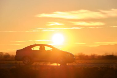 Gün batımında şehir içi yolda hızlı giden bir araba. Akşamları otoyol trafiği