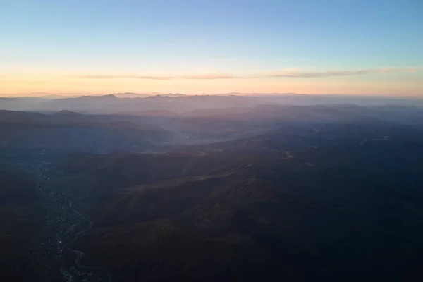 Aerial view of dark mountain hills at sunset. Hazy peaks and misty valleys in evening — 图库照片