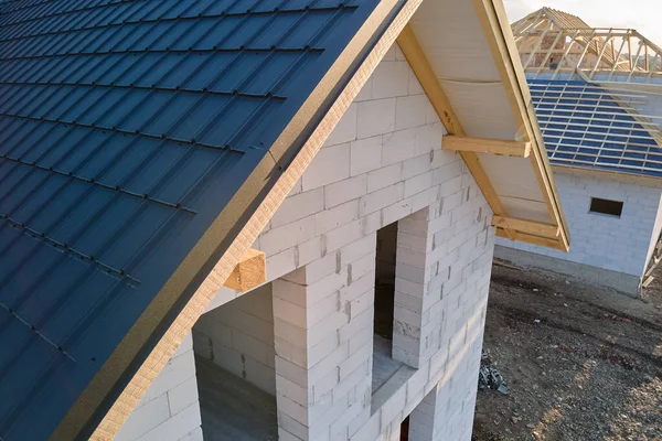 Vista aérea de casa inacabada con paredes de hormigón ligero aireado y marco de techo de madera cubierto con azulejos metálicos en construcción — Foto de Stock