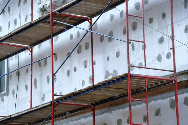 Fasáda budovy v rámci rekonstrukce pracuje s rámem stavebního lešení. Izolace stěn z polystyrénových plechů pro energeticky úsporné domácnosti — Stock fotografie