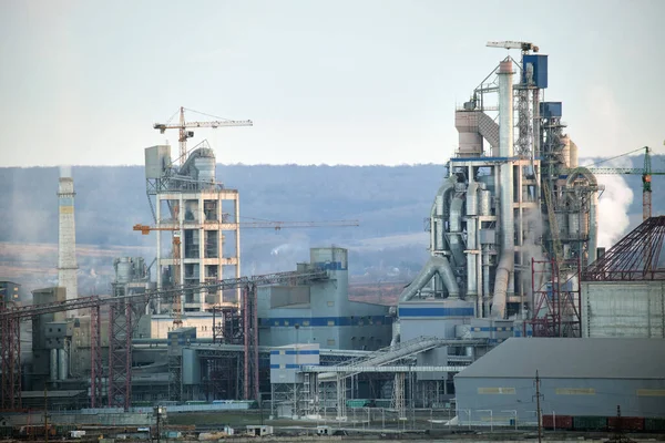 Zementwerk mit hoher Fabrikstruktur und Turmdrehkranen im Industriegebiet. Fertigung und globales Branchenkonzept — Stockfoto
