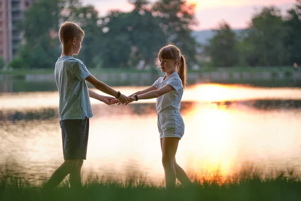 Szczęśliwe rodzeństwo trzymające się razem za ręce w letnim parku. Młode dzieci brat i siostra relaksujący na świeżym powietrzu. Rodzinna miłość i koncepcja relacji — Zdjęcie stockowe