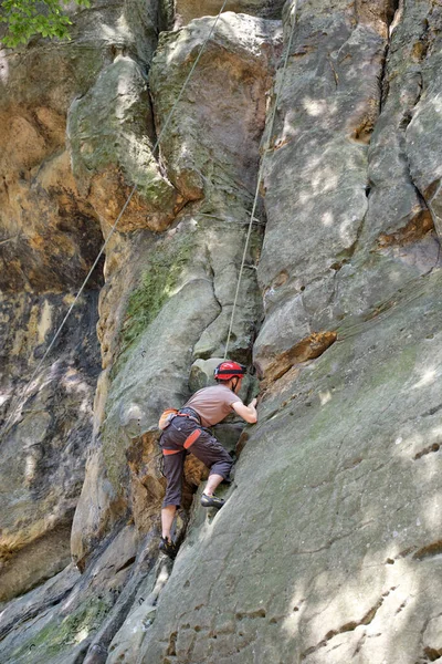 强壮的男性攀登者爬上陡峭的岩石山墙.运动员克服了困难的路线。从事极端体育业余爱好的概念 — 图库照片