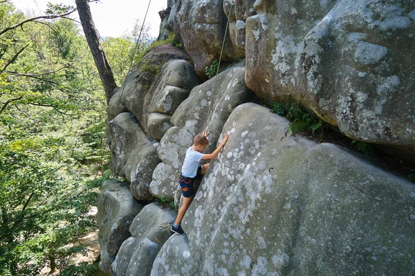 Kleiner Junge klettert steile Felswand hinauf. Kinderkletterer bewältigt anspruchsvolle Route Engagement im Extremsportkonzept — Stockfoto